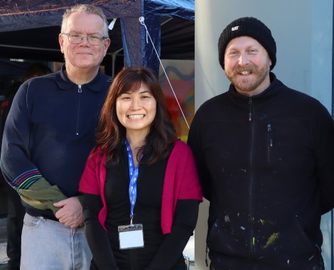 Two men and a woman smile for a photograph.